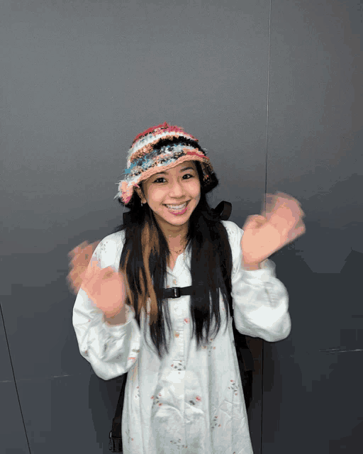 a girl wearing a hat and a white shirt is waving