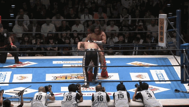 a wrestling match is being watched by a group of men wearing jerseys with the numbers 10 16 and 3