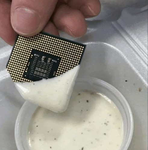 a chip is dipped in ranch dressing in a plastic container