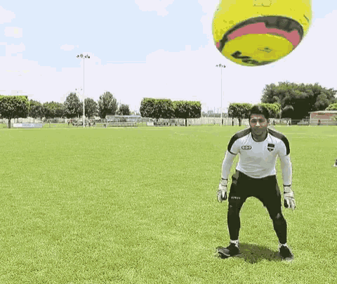 a soccer player in a white shirt with the word audi on it stands in front of a yellow soccer ball