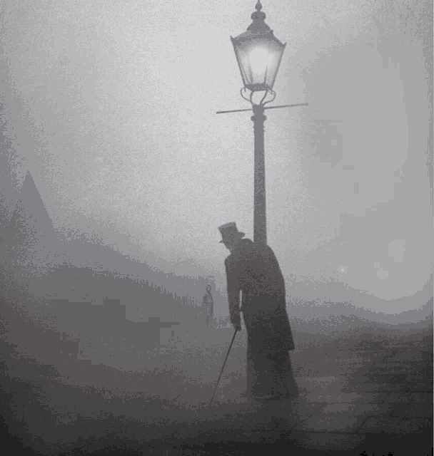 a man in a top hat and coat is standing next to a street light in the fog