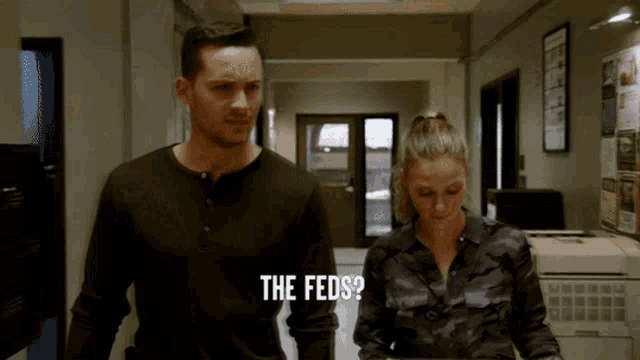 a man and a woman are walking down a hallway and the man asks the feds