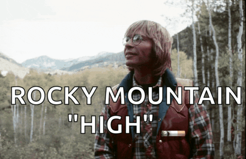 a man in a plaid shirt is standing in the woods with the words rocky mountain " high " behind him