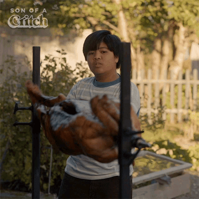 a boy is holding a large piece of meat in front of a sign that says son of a gift