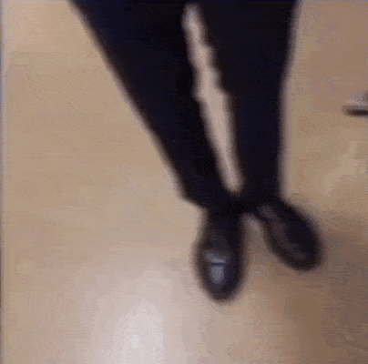 a person 's feet are visible in a blurry photo while walking on a wooden floor .