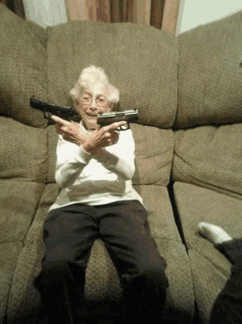 an older woman is sitting on a couch holding a gun