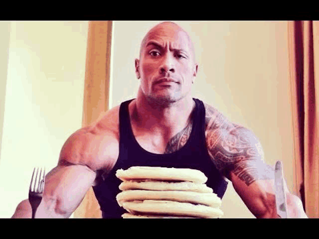 the rock is holding a stack of pancakes in his hands .