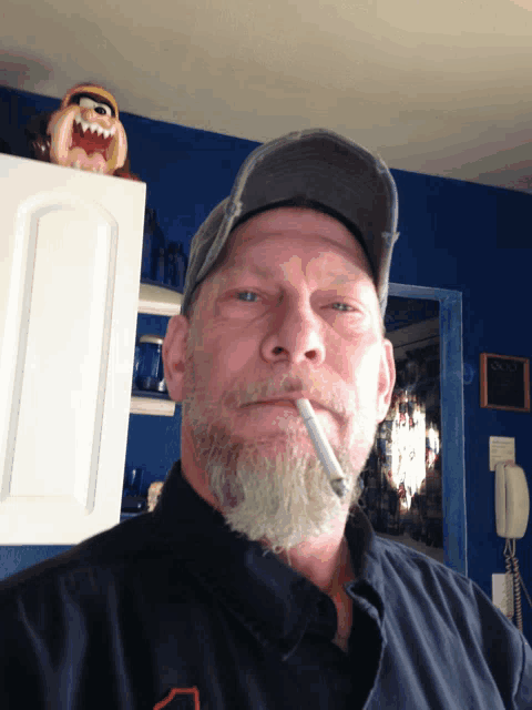 a man with a beard is smoking a cigarette in a kitchen