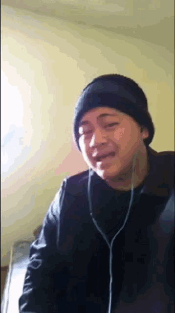 a man wearing headphones and a beanie is making a face