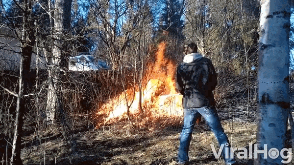 a man is standing in front of a fire in the woods and the words viralhog are on the bottom