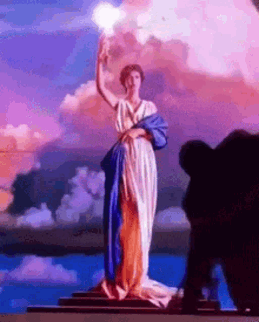 a statue of a woman in a blue and white dress is holding a torch in front of a cloudy sky .