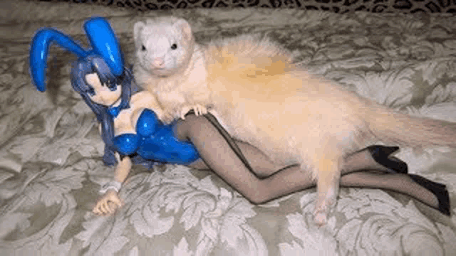 a ferret is laying on top of a figurine of a woman .