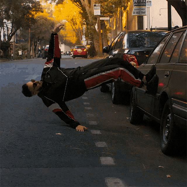 a man is doing a handstand on the side of a street in front of a sign that says " alquiler "