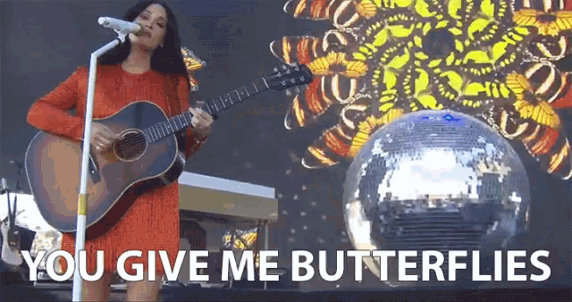 a woman singing into a microphone while holding a guitar with the words " you give me butterflies " on the bottom