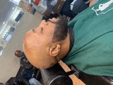 a man in a green shirt is laying down in a chair with his head down .