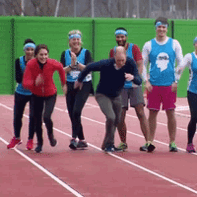 a group of people are running on a track and one of them is wearing a blue shirt with a ghost on it