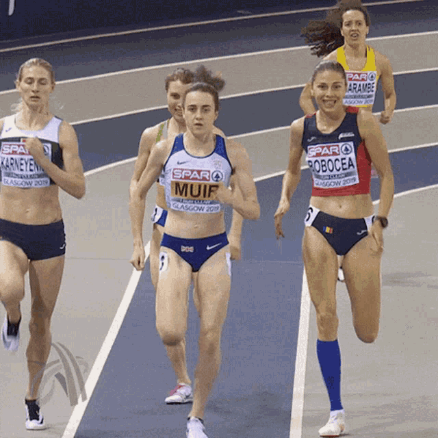 a group of female athletes are running on a track and one of them has the word muif on her shirt