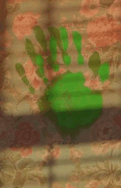 a green handprint on a floral background is visible through a window .