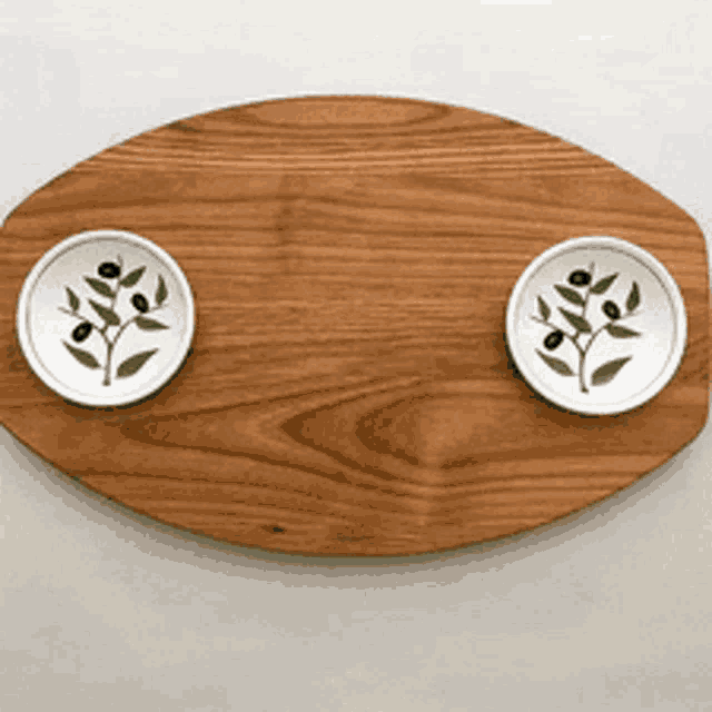 a wooden tray with two bowls on it with olives on them