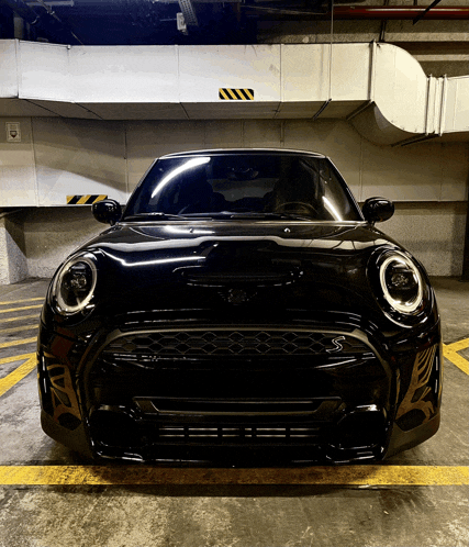 a black mini cooper is parked in a underground parking garage