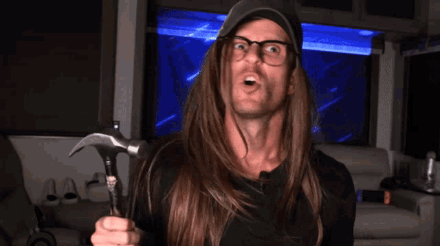 a man with long hair is holding a hammer and making a funny face