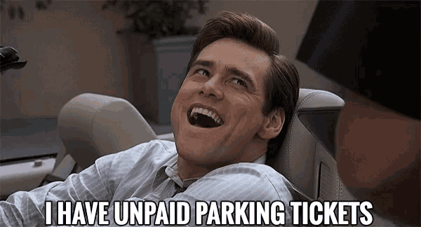 a man is sitting in a car laughing and saying i have unpaid parking tickets