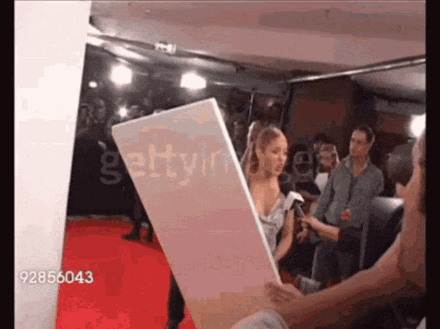 a woman on a red carpet is being interviewed by a man holding a sign that says gettyimages on it