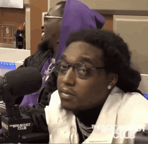 a man wearing glasses is sitting in front of a microphone that says the breakfast club