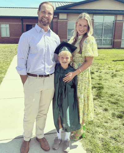 a man and woman pose with a young boy in a green cap and gown