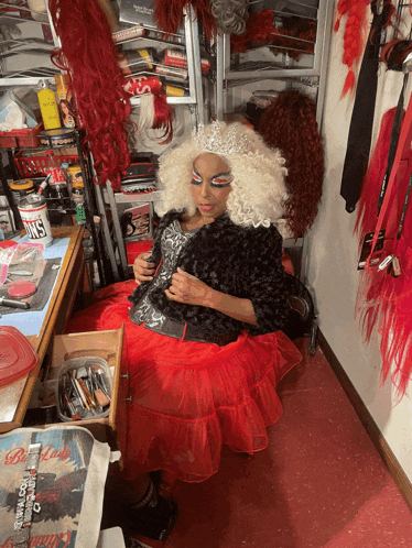 a woman in a red dress is sitting in front of a drawer that has a magazine on it that says ' hollywood '