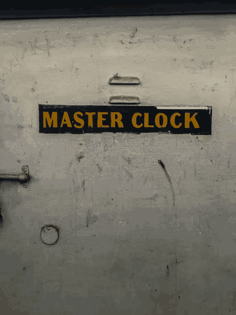 a sign on a wall that says master clock in yellow