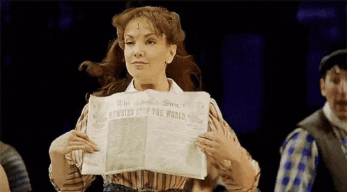 a woman is holding a newspaper in her hands in a theater .