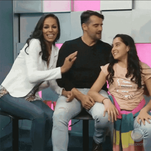 a woman sitting next to a man and a girl wearing a shirt that says ' i love you ' on it