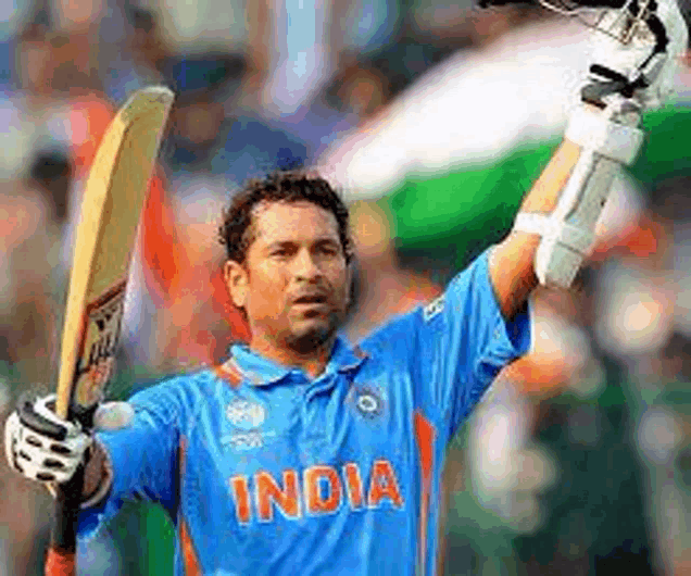 a man in a blue india shirt is holding a bat in his hand .