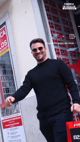 a man wearing sunglasses and a black sweater is standing in front of a ray-ban store