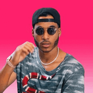 a man wearing sunglasses , a baseball cap , and a snake on his shirt .