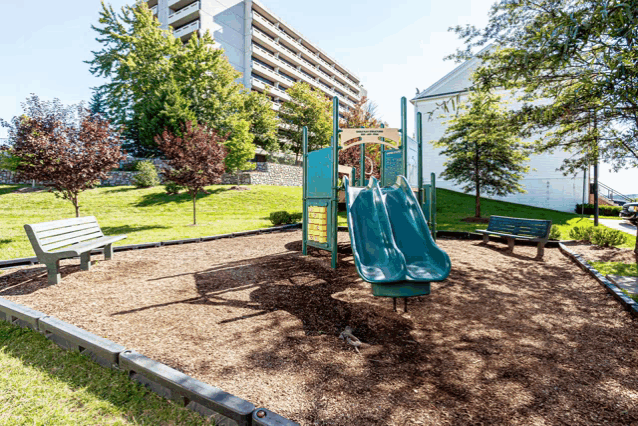 a playground with a slide and a bench in front of a building