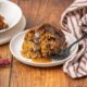 Christmas pudding served on a white plate with brown sugar sauce.