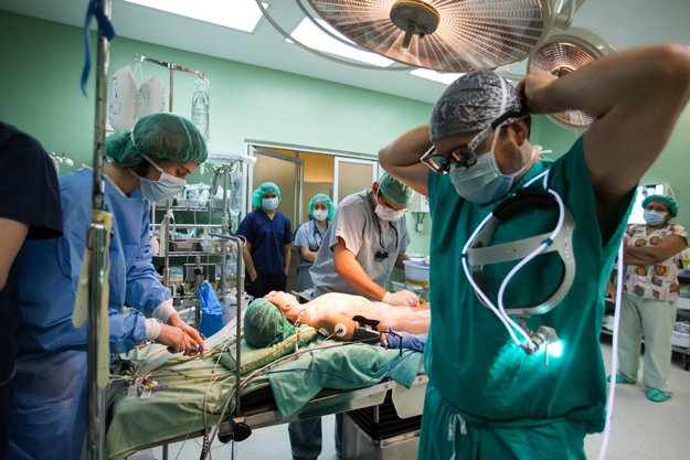 Dr. Rodrigo Soto adjusts his surgical headlamp while local surgeon Dr. Jorge Ochoa cleans a patient prior to iodine application.