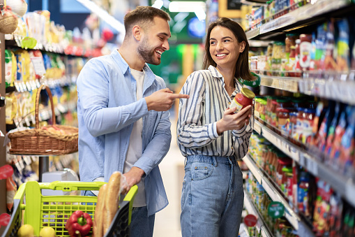 Young happy couple with the cart shopping in supermarket