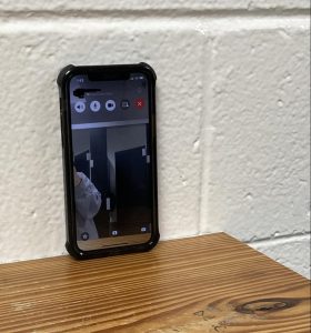 Photo illustration of a phone propped on the shelf of the girls' bathroom.