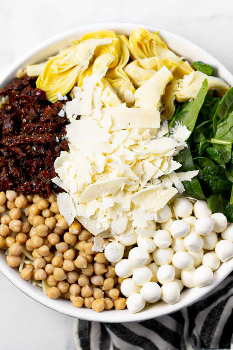 Large white bowl filled with ingredients to make pasta salad 