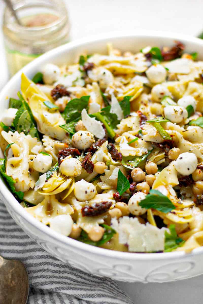 Close up shot of a bowl of sun dried tomato pasta salad garnished with fresh parsley 