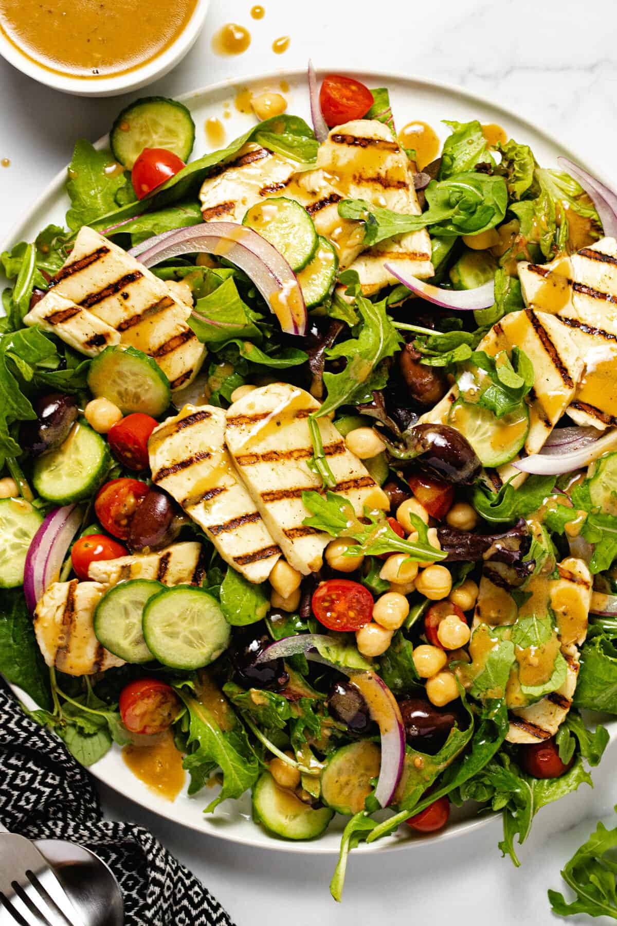 White plate filled with mixed greens and grilled halloumi cheese