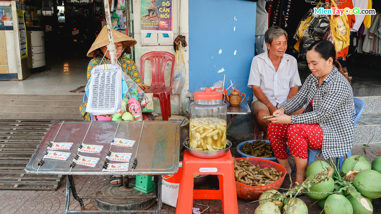 Cô hàng vừa bán hàng ngoài chợ vừa gọt vỏ me để làm thêm