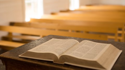 Bible on wooden pulpit with pews in background