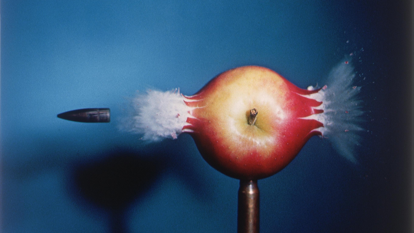 Bullet striking through a red apple.