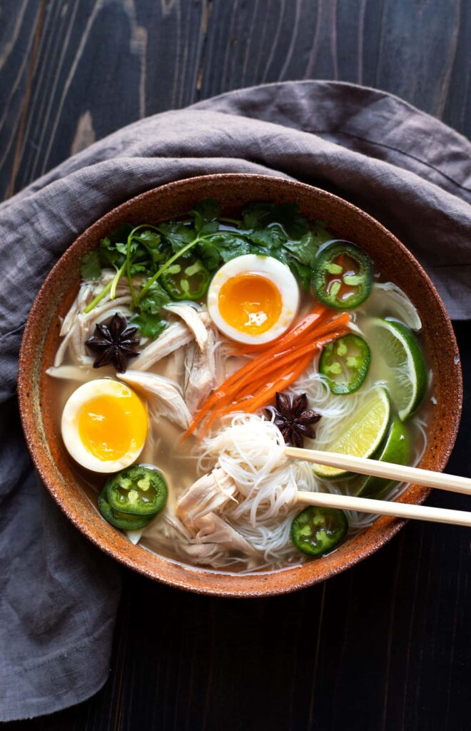 bowl of chicken pho with soft boiled egg jalapeno cilantro rice noodles