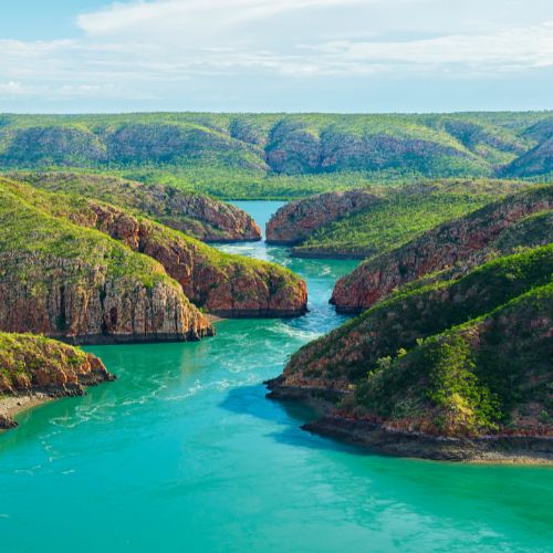 Aerial view of a turquoise river winding through a rugged gorge with lush greenery in Australia