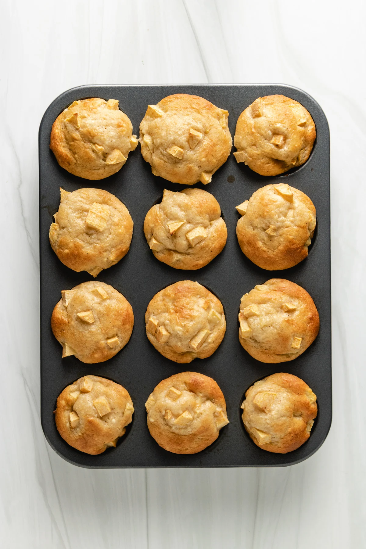 Top down view of a pan of apple cinnamon muffins.